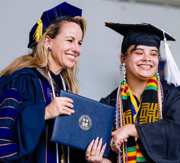 Kaitlynn Devitt (left) receives her degree at graduation. Devitt was awarded the 米歇尔·凯杰出记者奖 for her photojournalism work. 