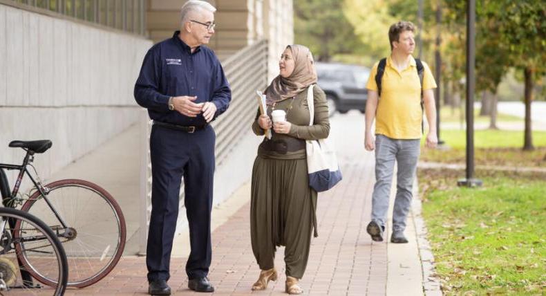 student and professor walking and talking outdoors on campus 